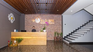 A reception area with a wooden desk, a brick wall, and a staircase. - SOCO Hotel (Da Nang)
