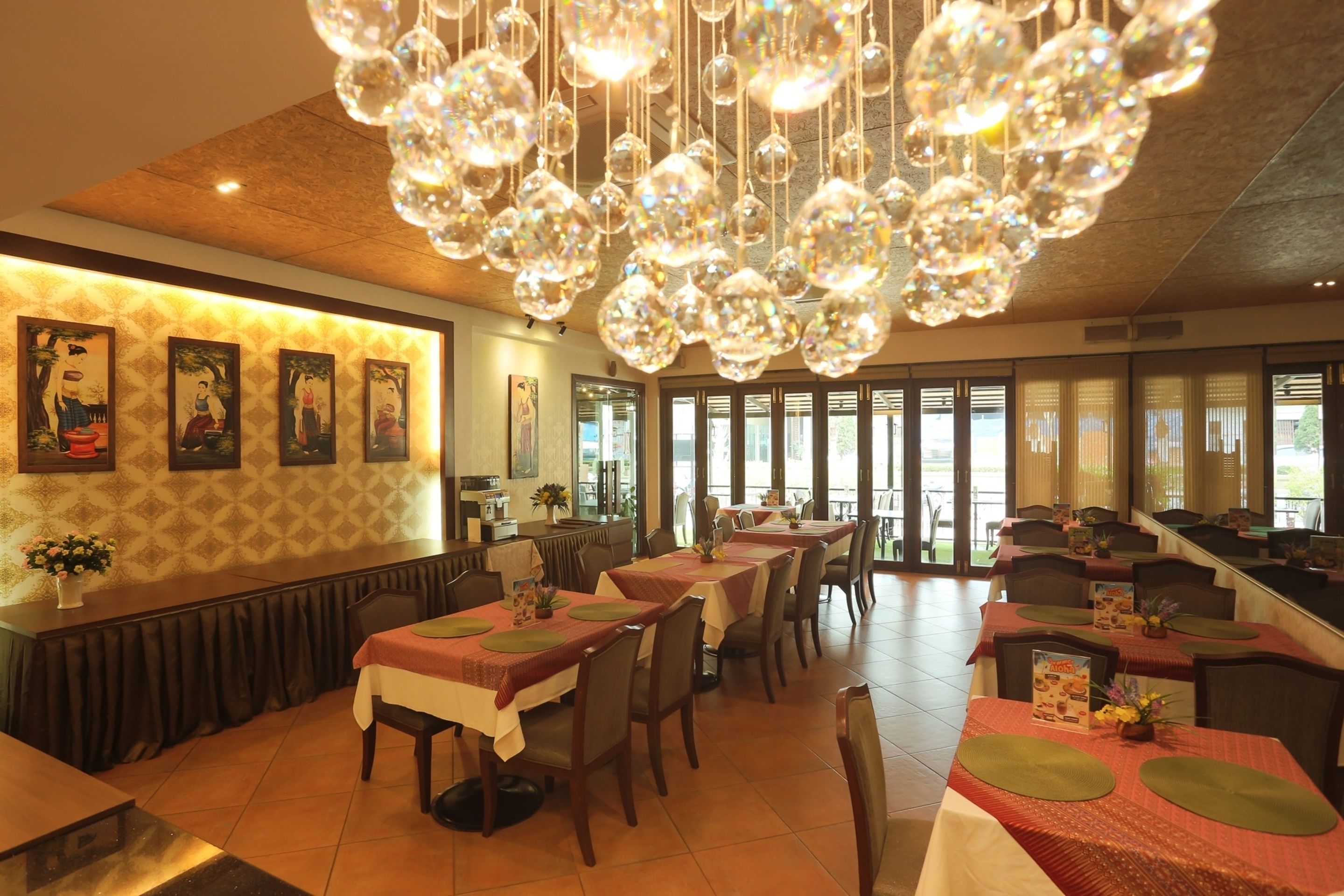 A restaurant with multiple tables, a bar area, and a large chandelier.