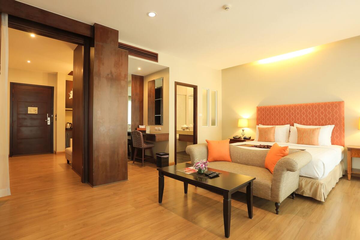 Una habitación de hotel con cama, sofá, mesa de centro, escritorio y silla.