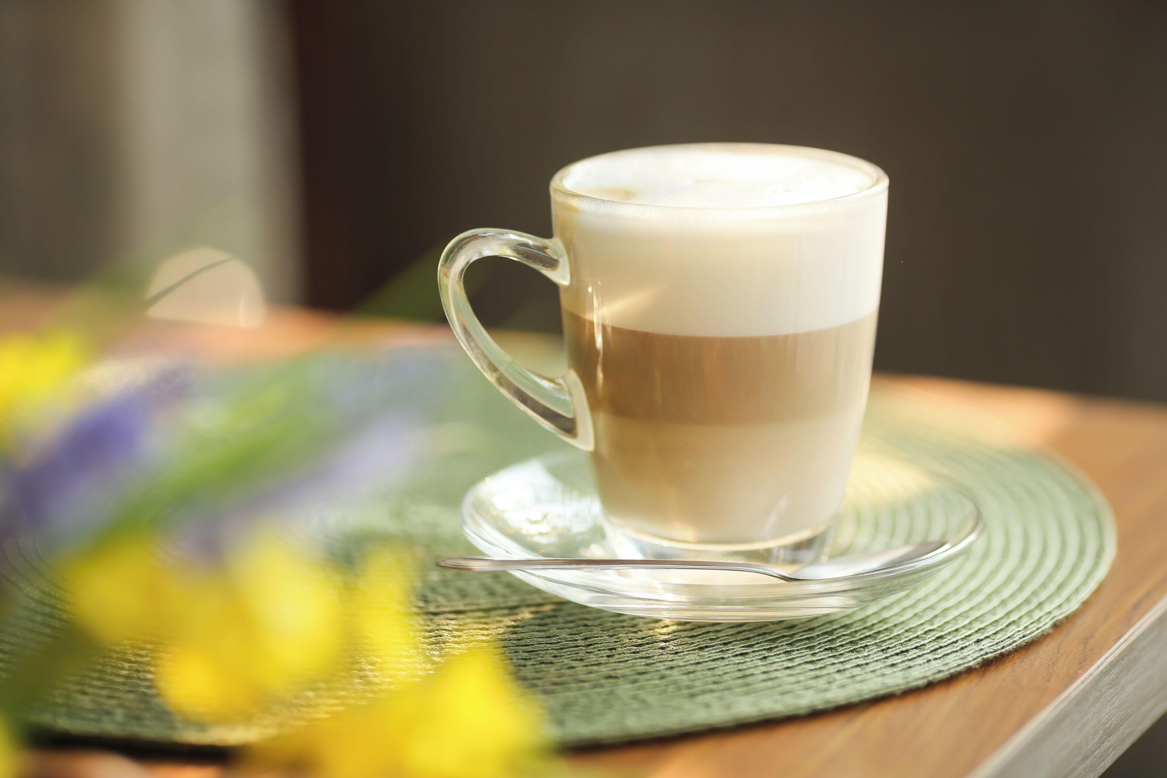 A cup of coffee on a saucer with a green placemat.