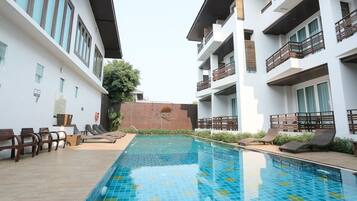 A swimming pool with lounge chairs and a brick wall in the background.