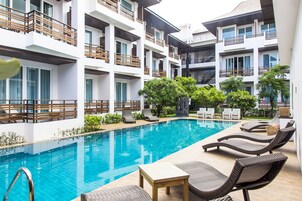Una piscina al aire libre, sillones reclinables de piscina