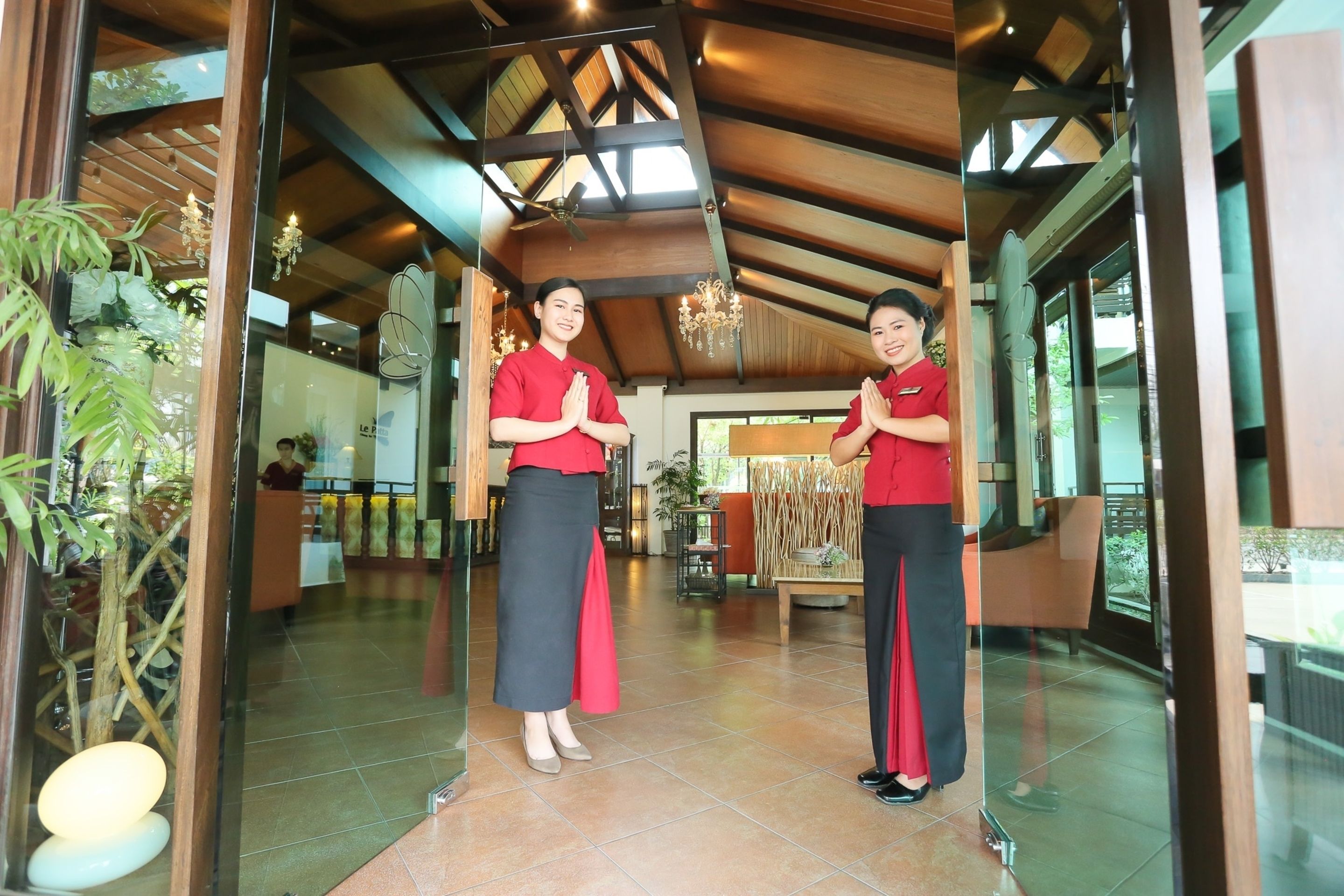 A reception area with wooden ceiling beams, a chandelier, and a reception desk.