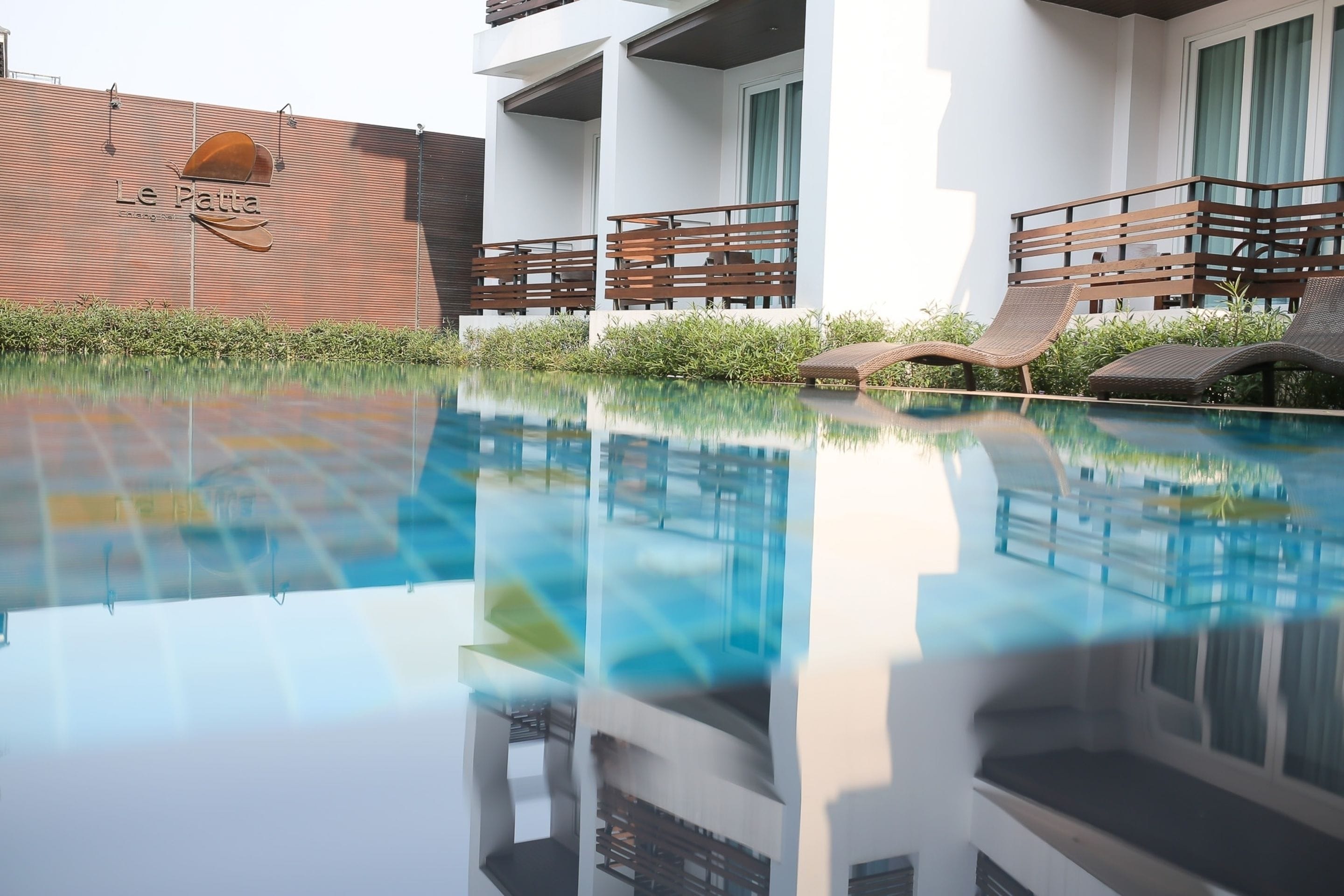 A modern hotel with a swimming pool, lounge chairs, and a brick wall with the hotel's name.