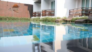 A modern hotel with a swimming pool, lounge chairs, and a brick wall with the hotel's name.