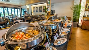 Un área de bufé con varias estaciones de comida, una estación de barista y un espacio de estar con mesas y sillas.