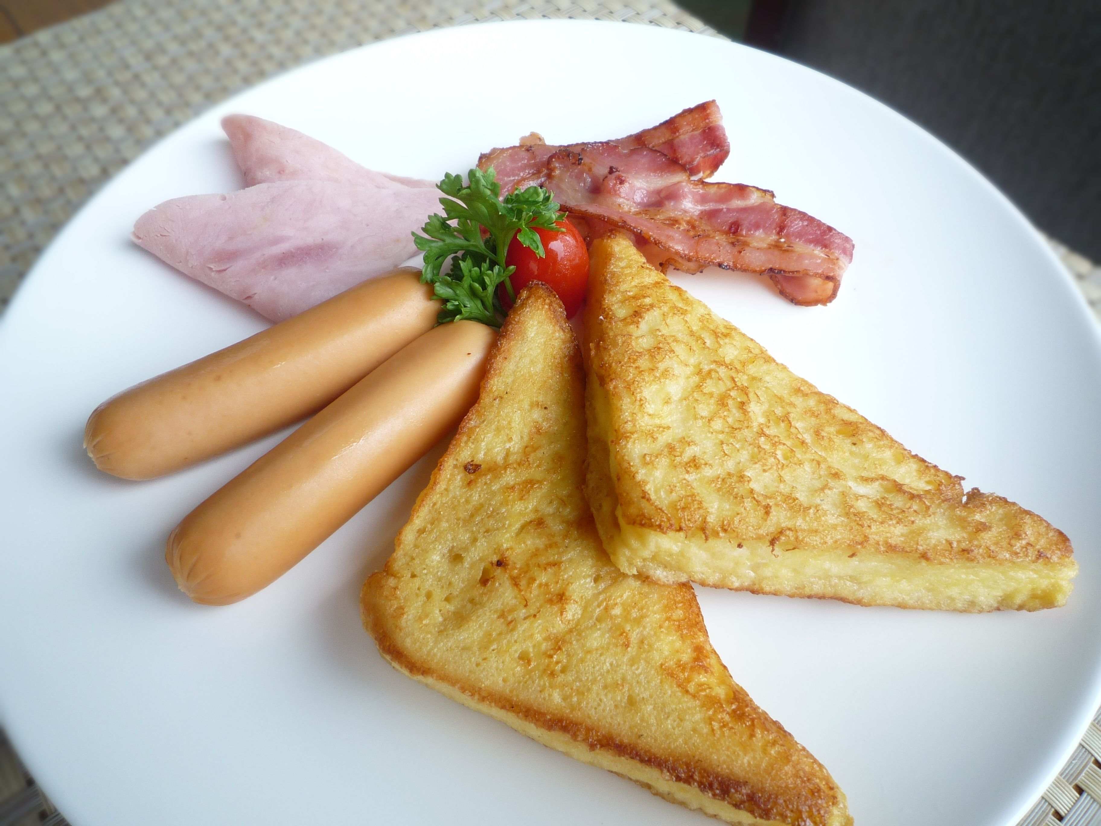 A plate with grilled ham, bacon, and grilled tomatoes.