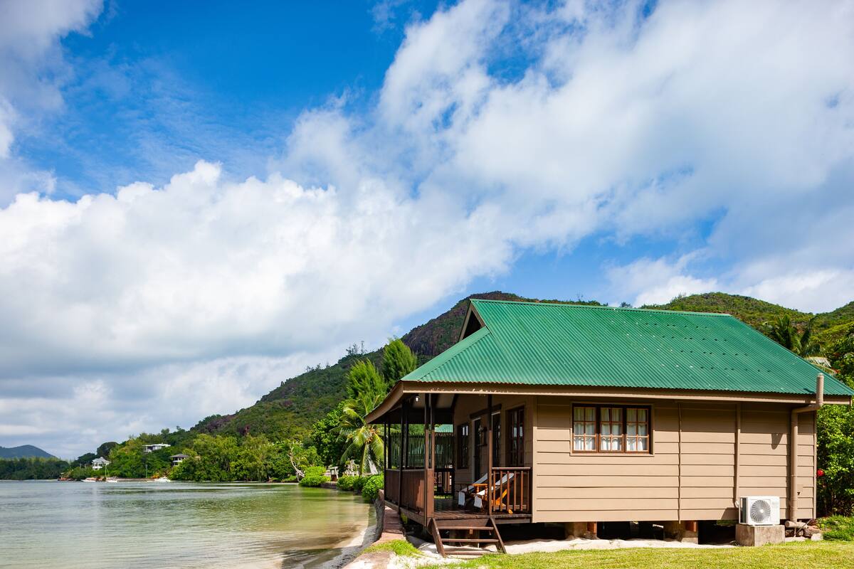 A single-story building with a green roof, a porch, and a small air conditioning unit on the side.