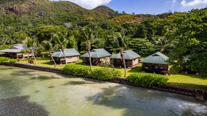 A resort with multiple bungalow-style buildings, a water body in the foreground, and lush greenery in the background. -  Le Vasseur La Buse Eco Resort (Praslin Island)