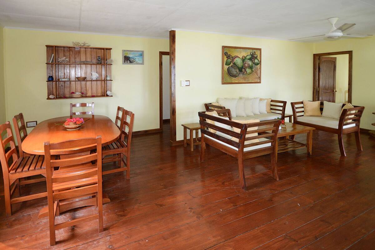 A dining area with a wooden table and chairs, a sofa, and a cabinet with decorative items.