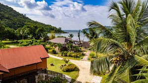 A resort with a red-roofed building, a pathway leading to a pool area, and a view of the sea and mountains. -  Le Vasseur La Buse Eco Resort (Praslin Island)