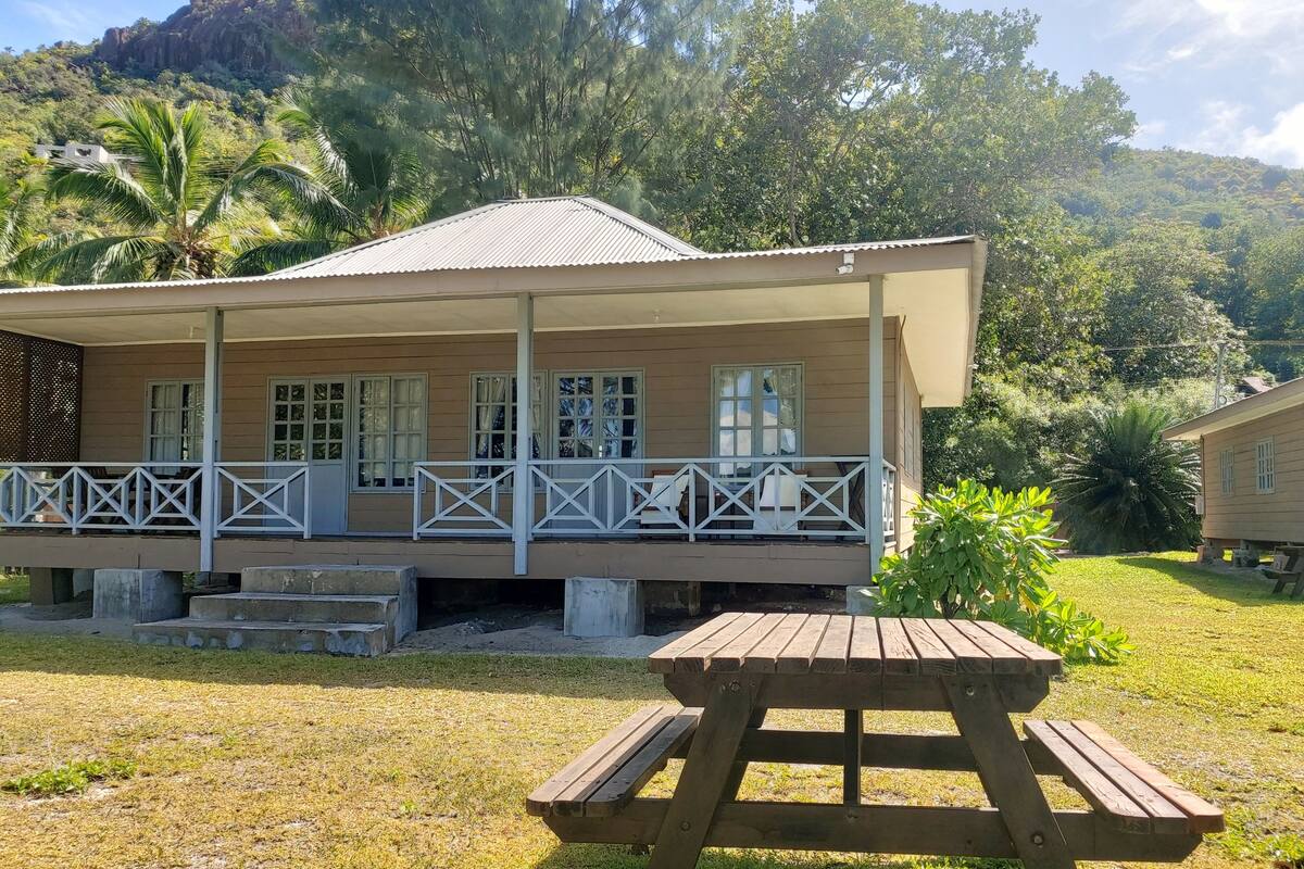 A two-story building with a covered porch and a picnic table in front.