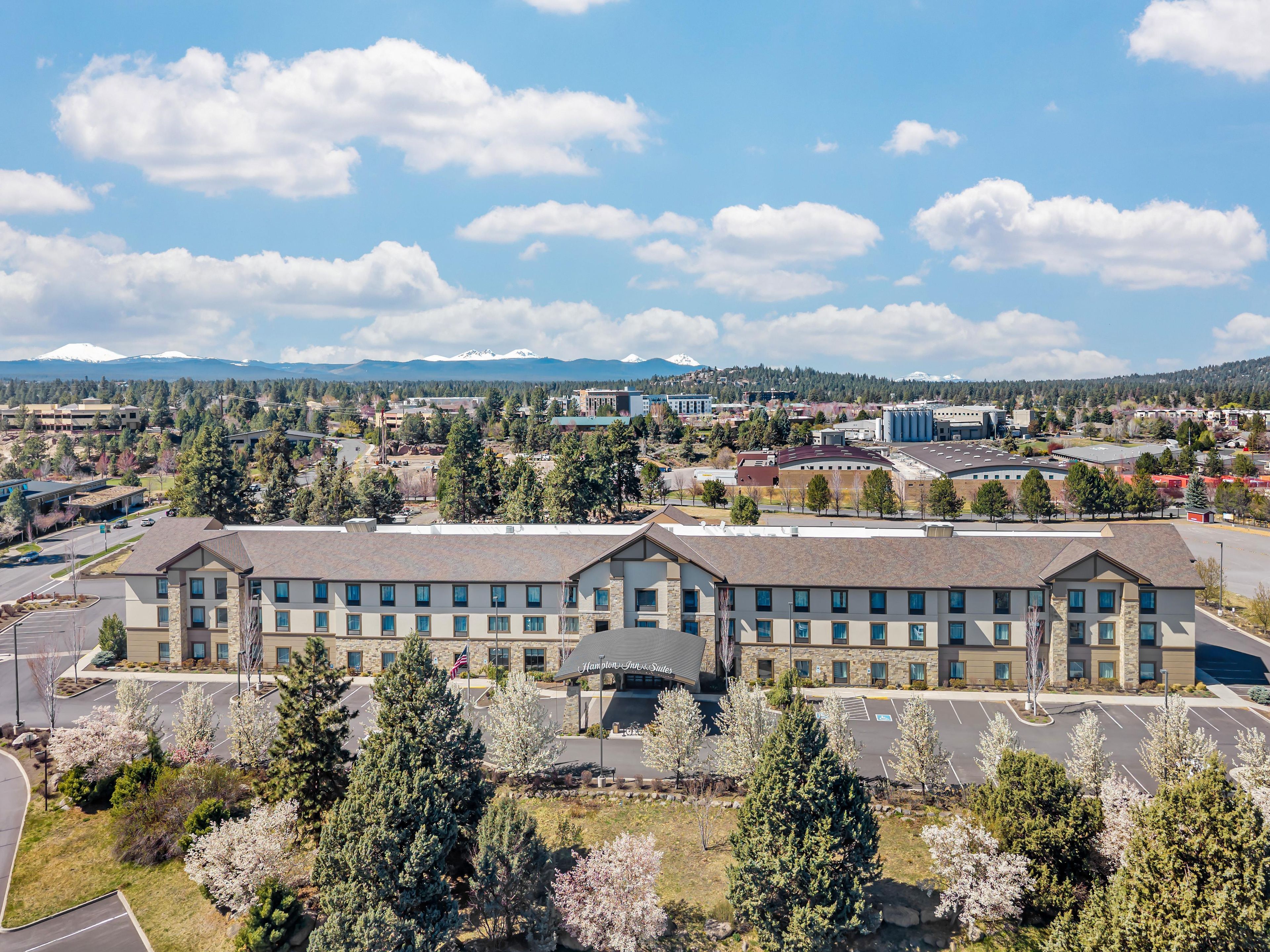 A hotel with a central courtyard, surrounded by parking and trees.