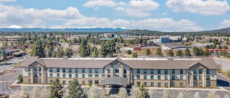 A hotel with a central courtyard, surrounded by parking and trees.