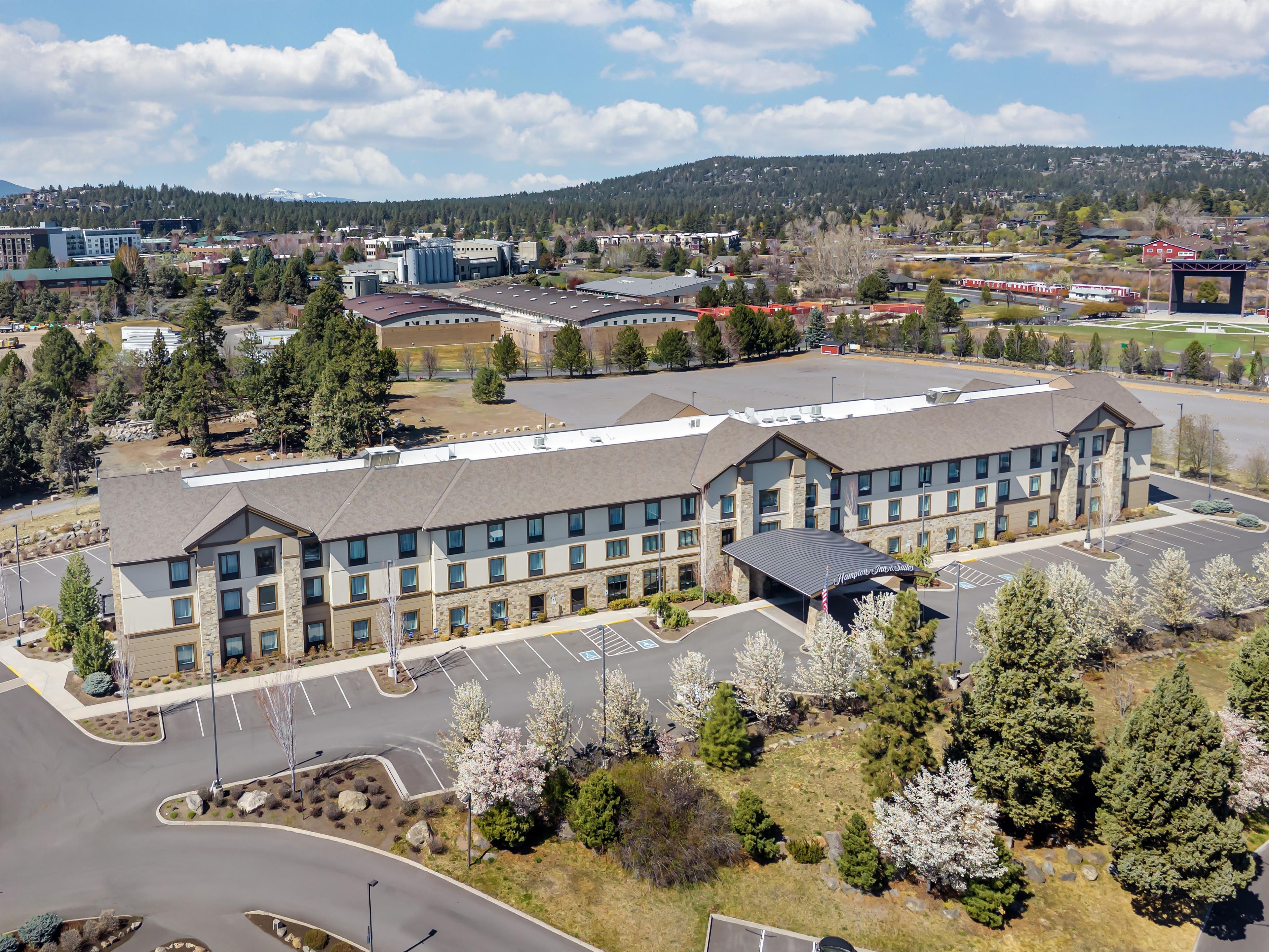 A multi-story hotel with a parking lot and a view of a mountainous landscape.