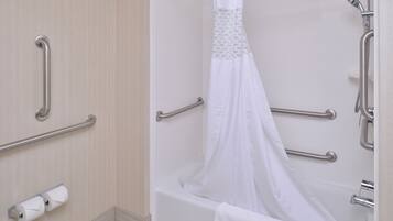 A bathroom with a bathtub, grab bars, and a shower curtain.