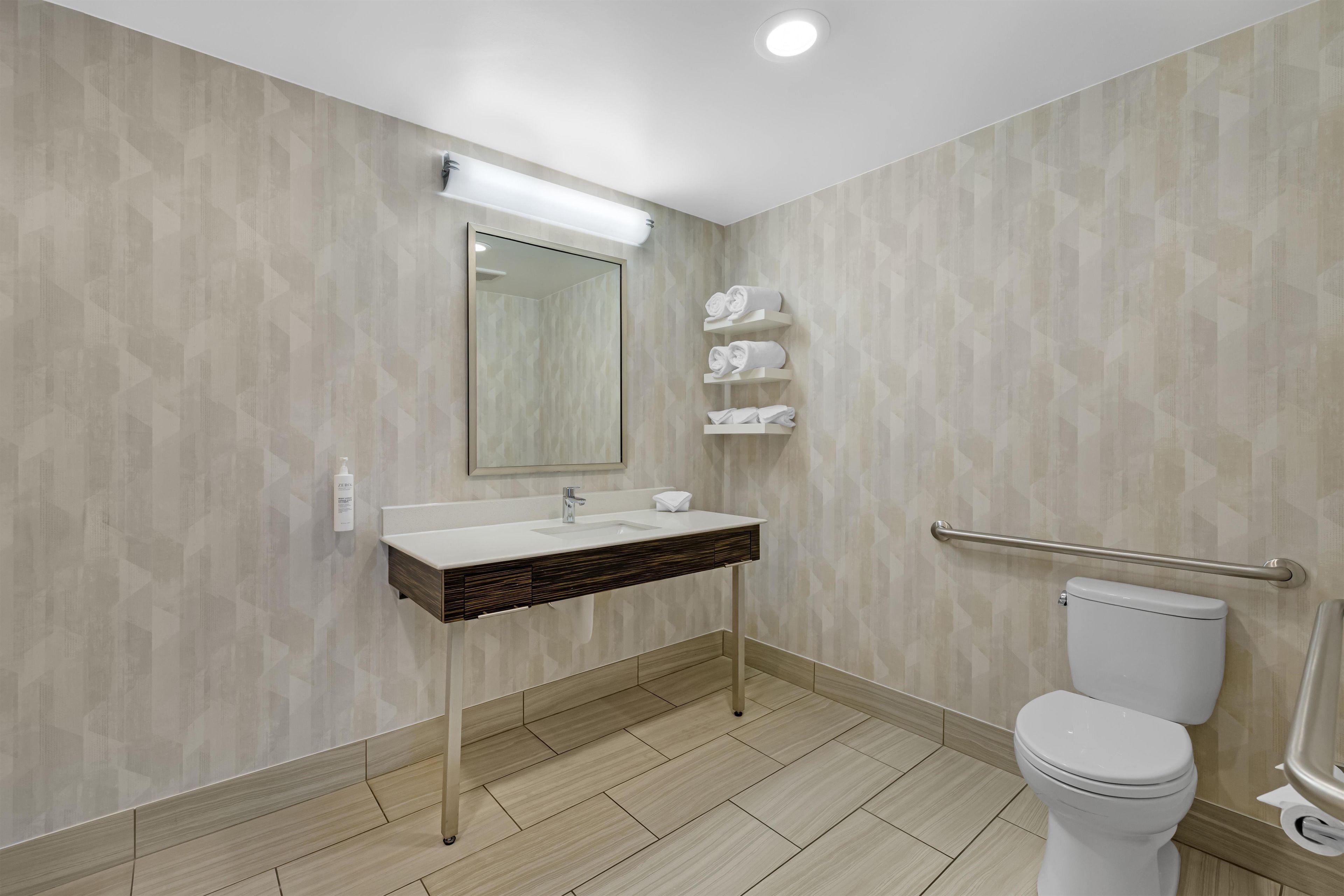 A modern bathroom with a vanity, toilet, and towel rack.