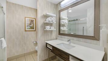 A modern bathroom with a large mirror, white sink, and towel racks.