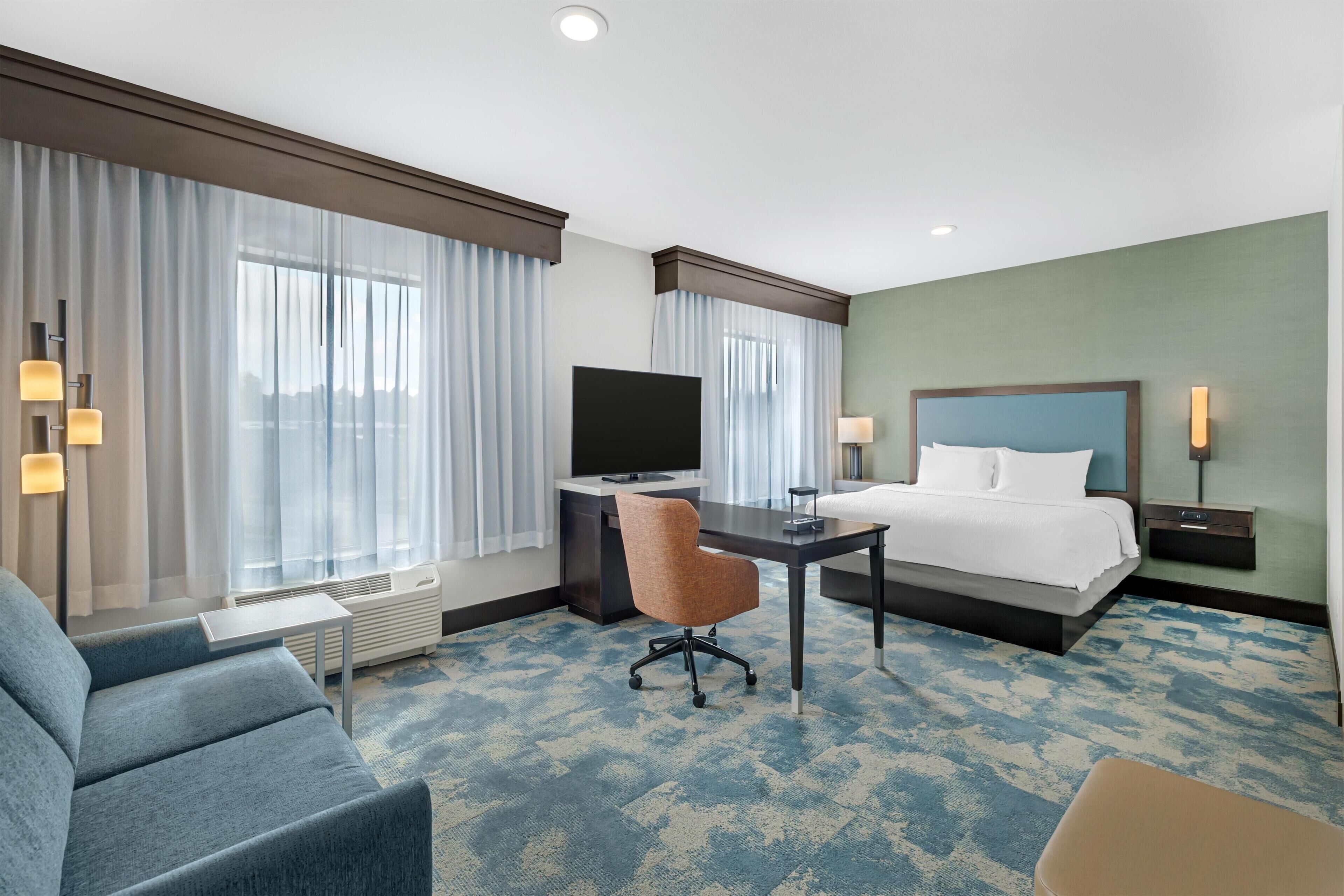 Une chambre d’hôtel équipée d’un lit, d’un bureau, d’une télévision et d’un coin salon.