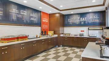 A kitchen area with a checkered floor, wooden cabinets, and a counter with food items.