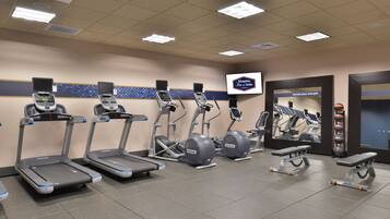 A gym with treadmills, elliptical machines, and a bench.