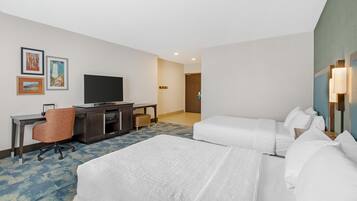 A hotel room with two beds, a desk with a chair, a television, and artwork on the wall.