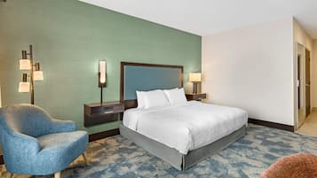 A hotel room with a bed, a chair, a nightstand, and a wall-mounted lamp.