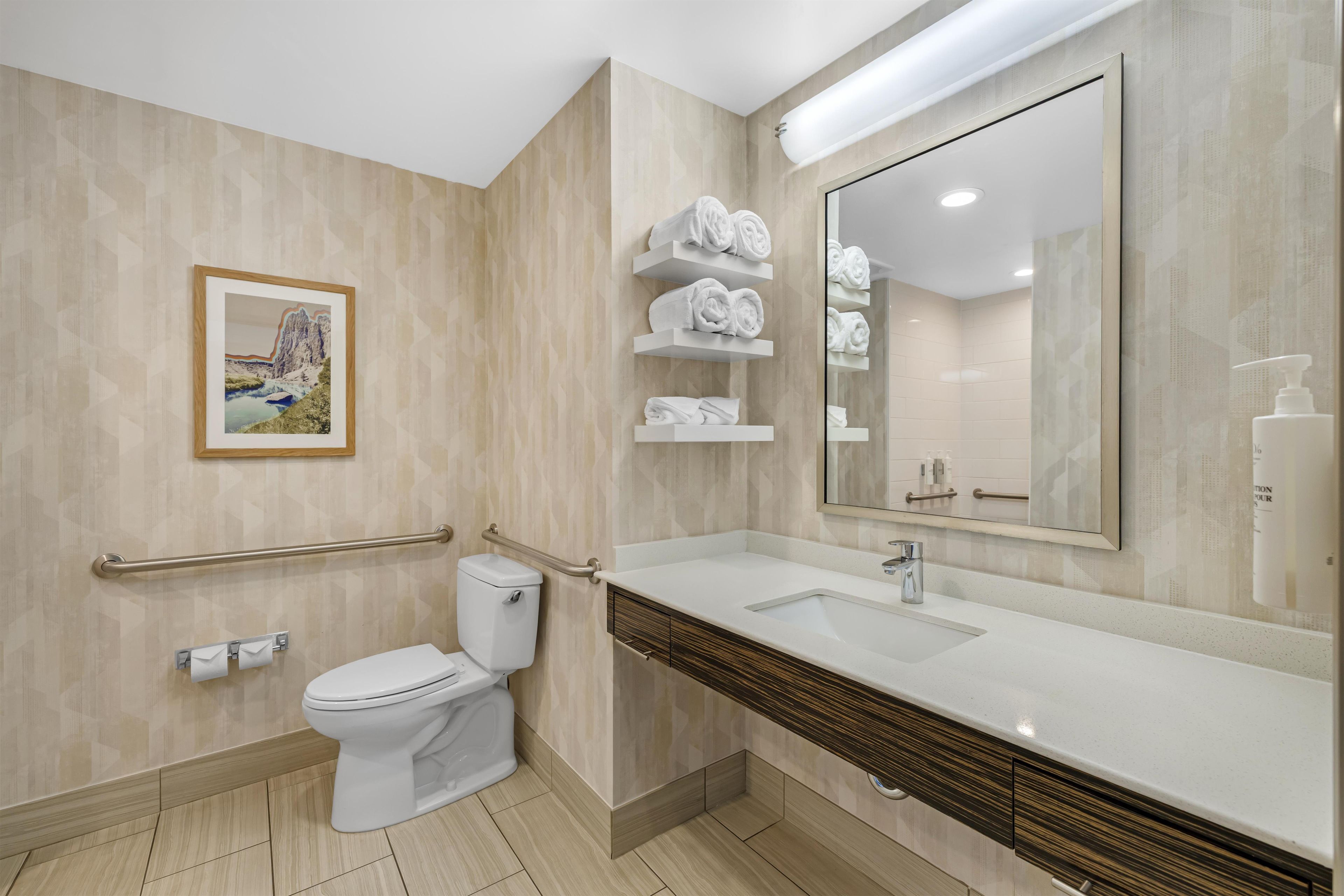 A modern bathroom with a toilet, sink, and towel racks.