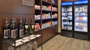 A suite shop with shelves stocked with snacks and beverages, and a display of wine bottles. - Hampton Inn & Suites Bend (Bend)