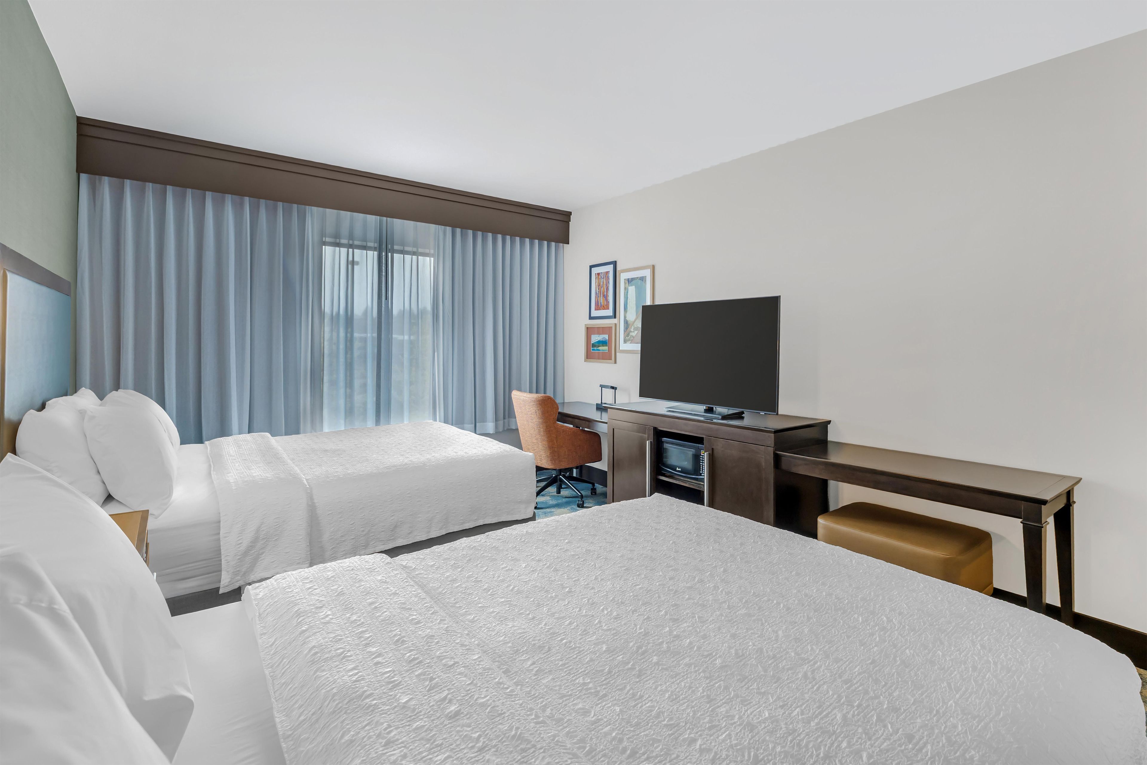 Een hotelkamer met twee bedden, een bureau, een flatscreen televisie en een stoel.