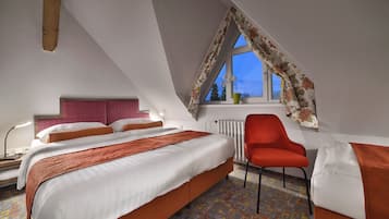 Ein Schlafzimmer mit einem großen Bett, einem roten Sessel, einem Fenster mit blumigem Vorhang und einer Heizung.