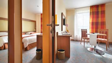 Een hotelkamer met een bed, een bureau, een stoel, een televisie en een raam met gordijnen.