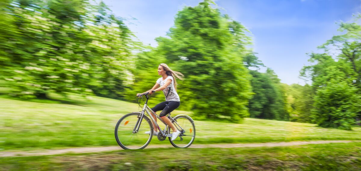 Una persona pedaleando en bicicleta por un sendero rodeado de vegetación.
