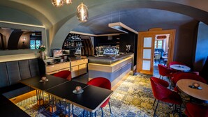 A modern bar area with a counter, seating, and a patterned carpet. - Maximilian Lifestyle Resort (Loucen)