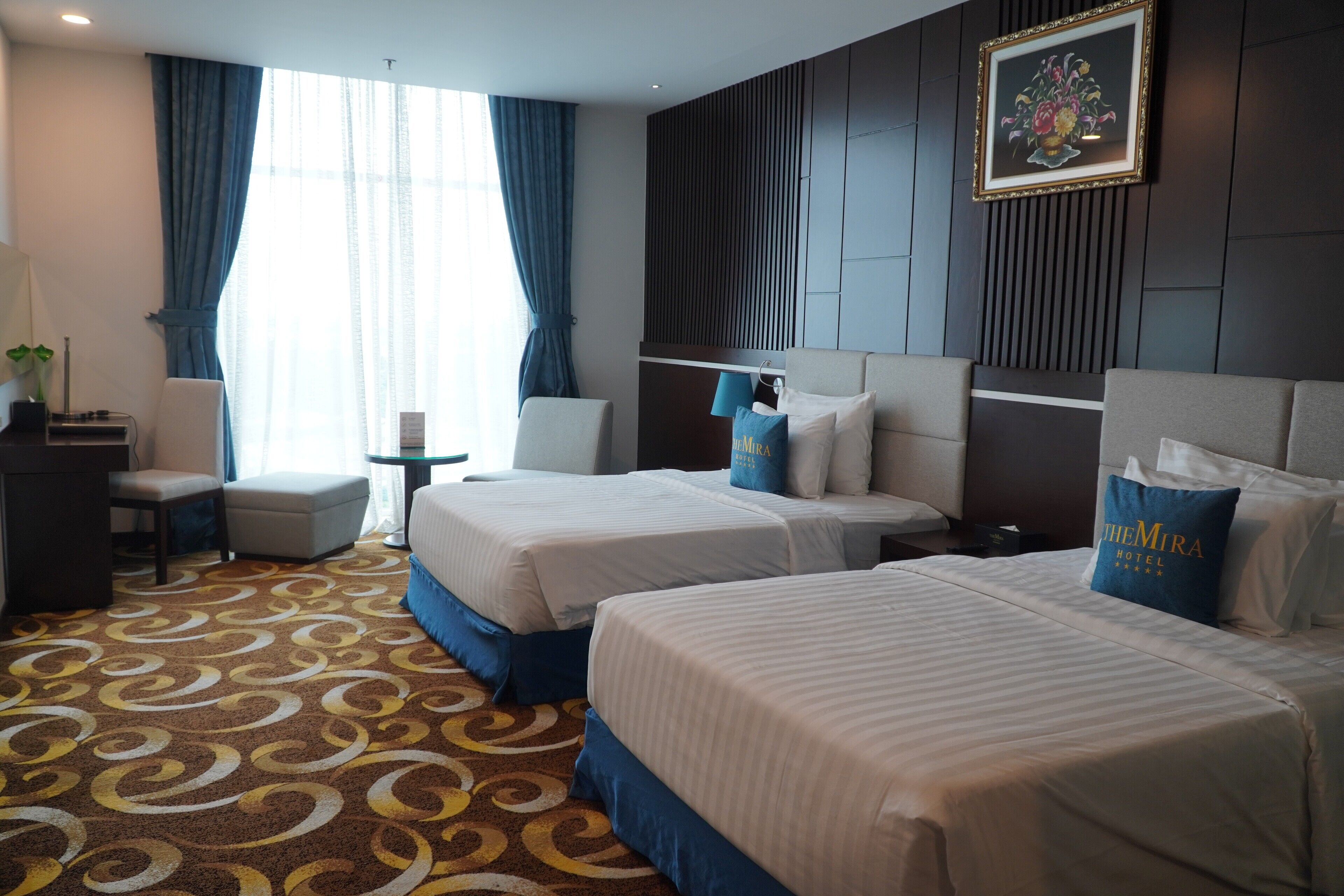 A hotel room with two beds, a desk, and a chair.