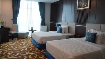 A hotel room with two beds, a desk, and a chair.