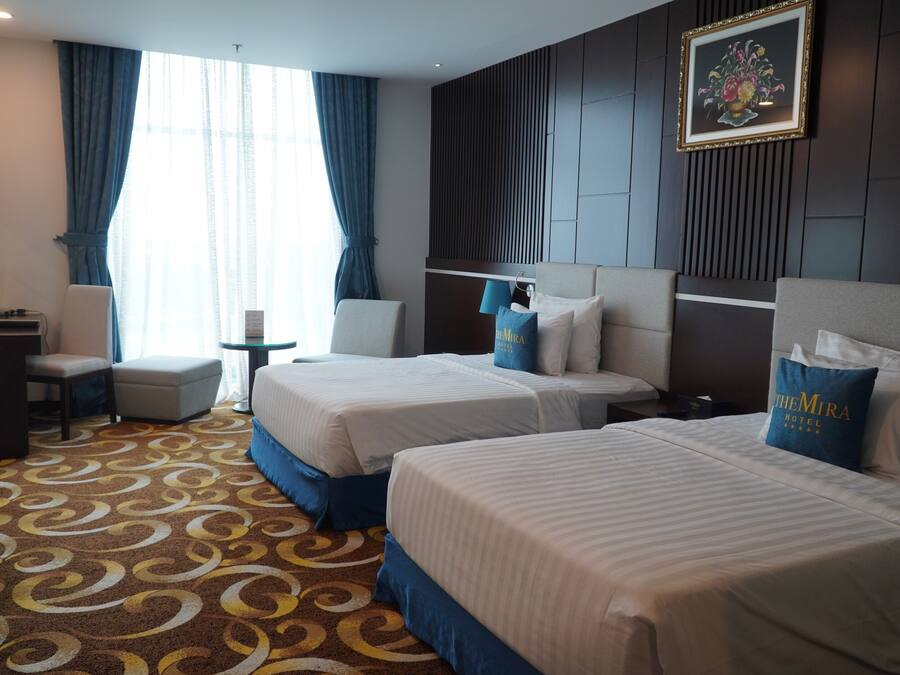A hotel room with two beds, a desk, and a chair.