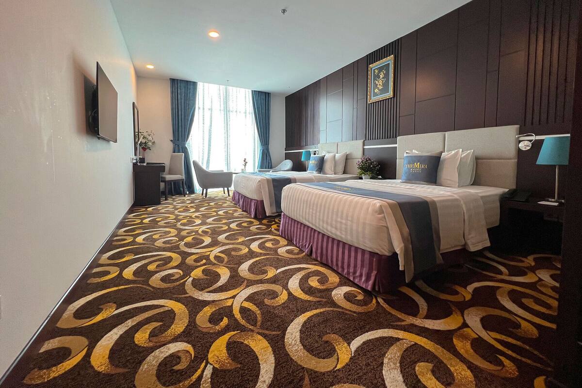 Une chambre d’hôtel avec deux lits, un bureau et une chaise.