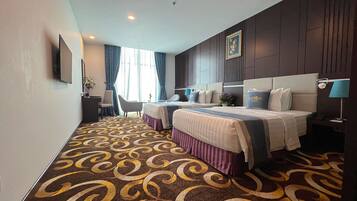 A hotel room with two beds, a desk, and a chair.