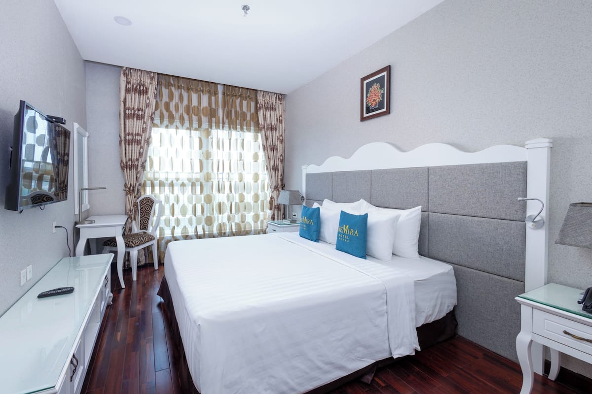 Une chambre d’hôtel avec un grand lit, une table de chevet, une télévision et une chaise.