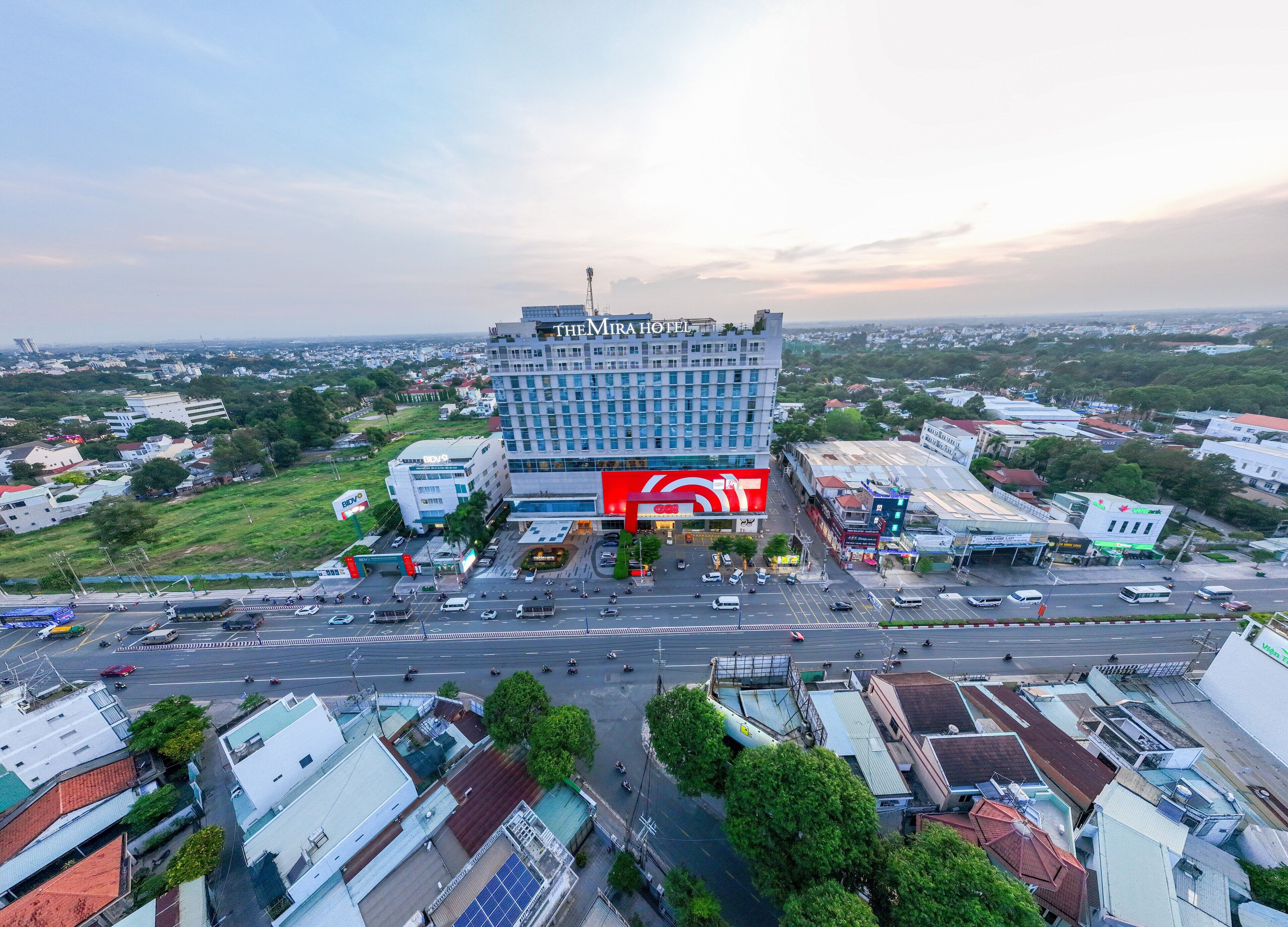A hotel with a prominent sign, surrounded by a busy street and other buildings.