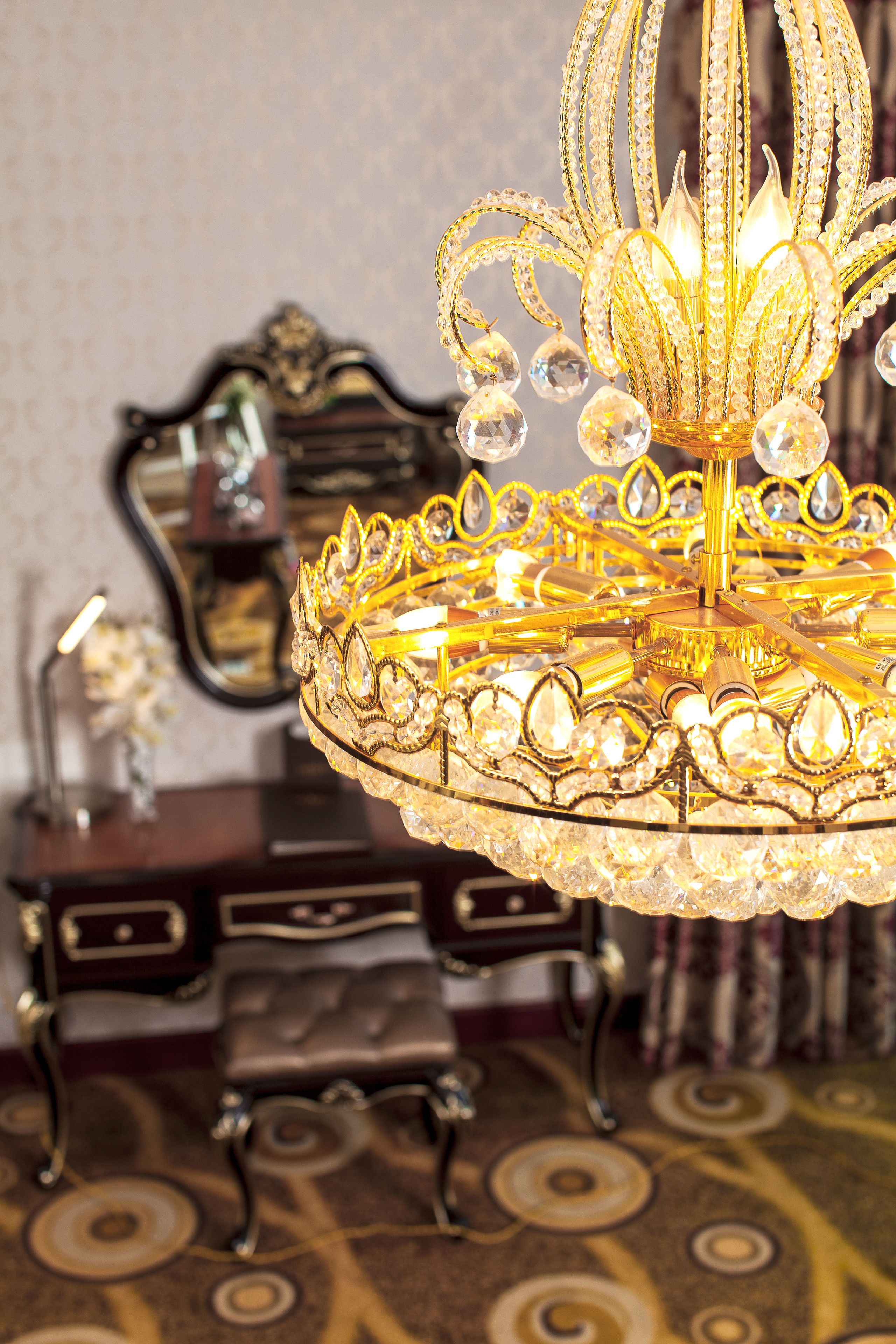Un candelabro con diseño dorado y de cristal, un espejo y una alfombra estampada.