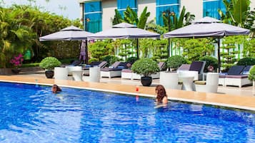 Una piscina al aire libre, sombrillas, sillones reclinables de piscina