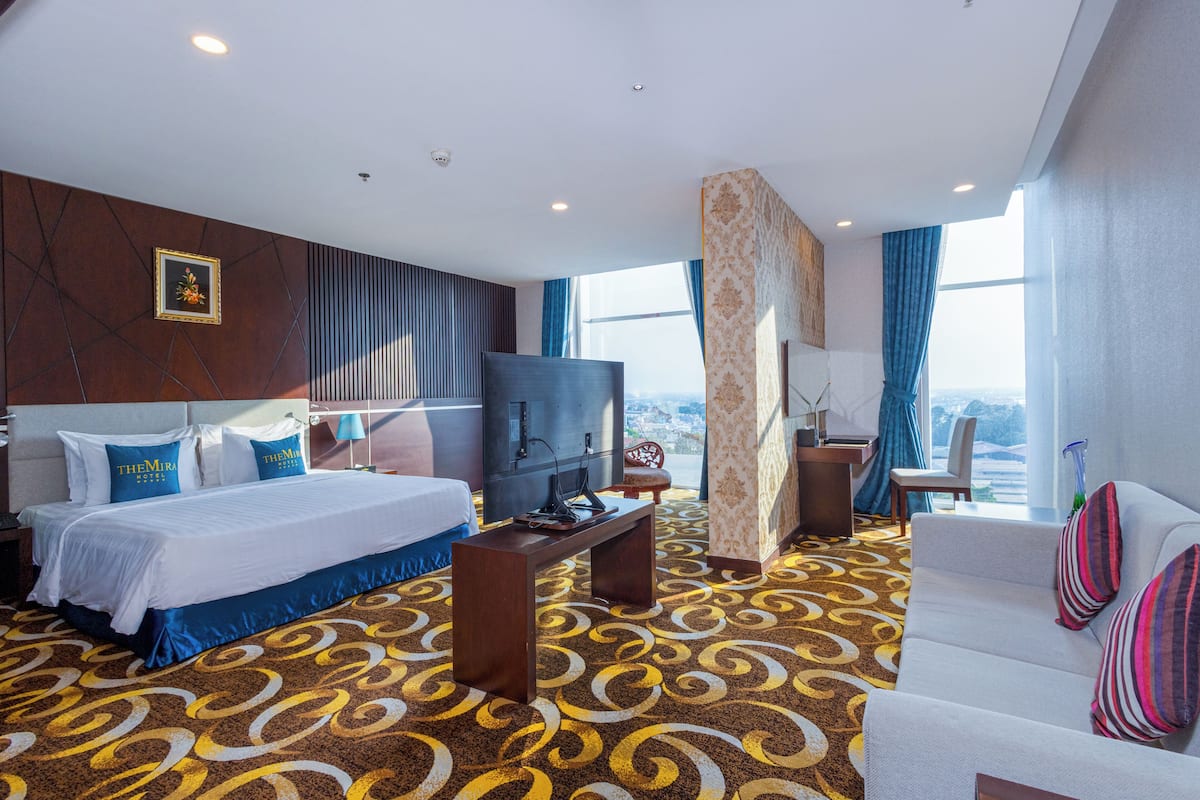 Une chambre d’hôtel avec un grand lit, une télévision, un bureau et un canapé.