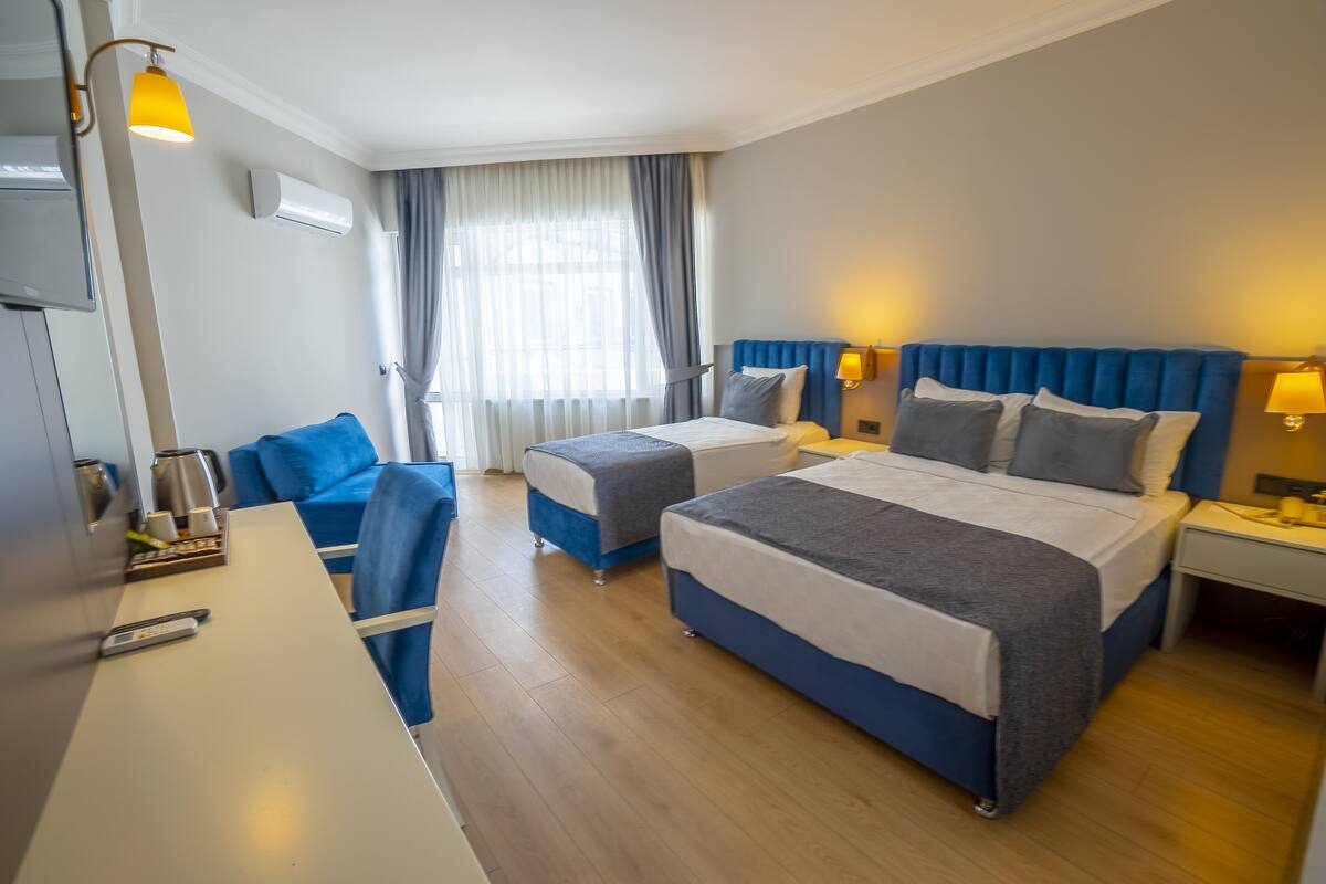 A hotel room with two beds, a desk, and a chair.