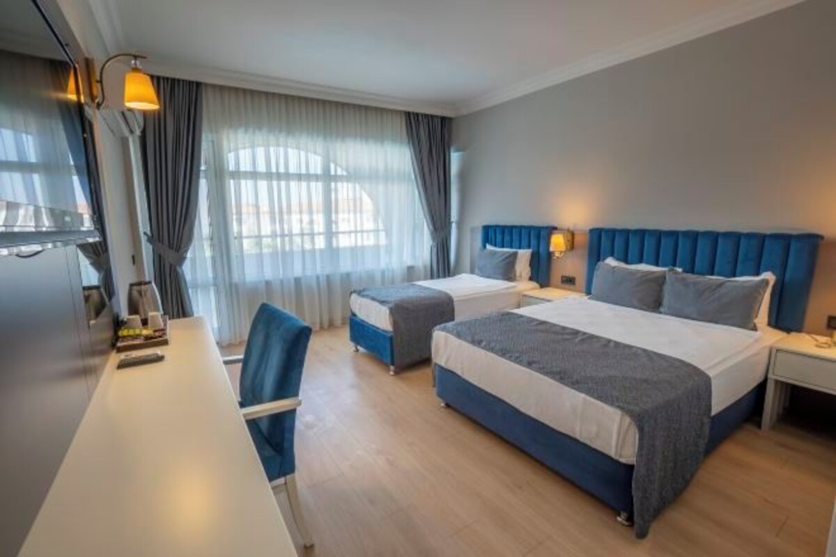 A hotel room with two beds, a desk, and a chair.