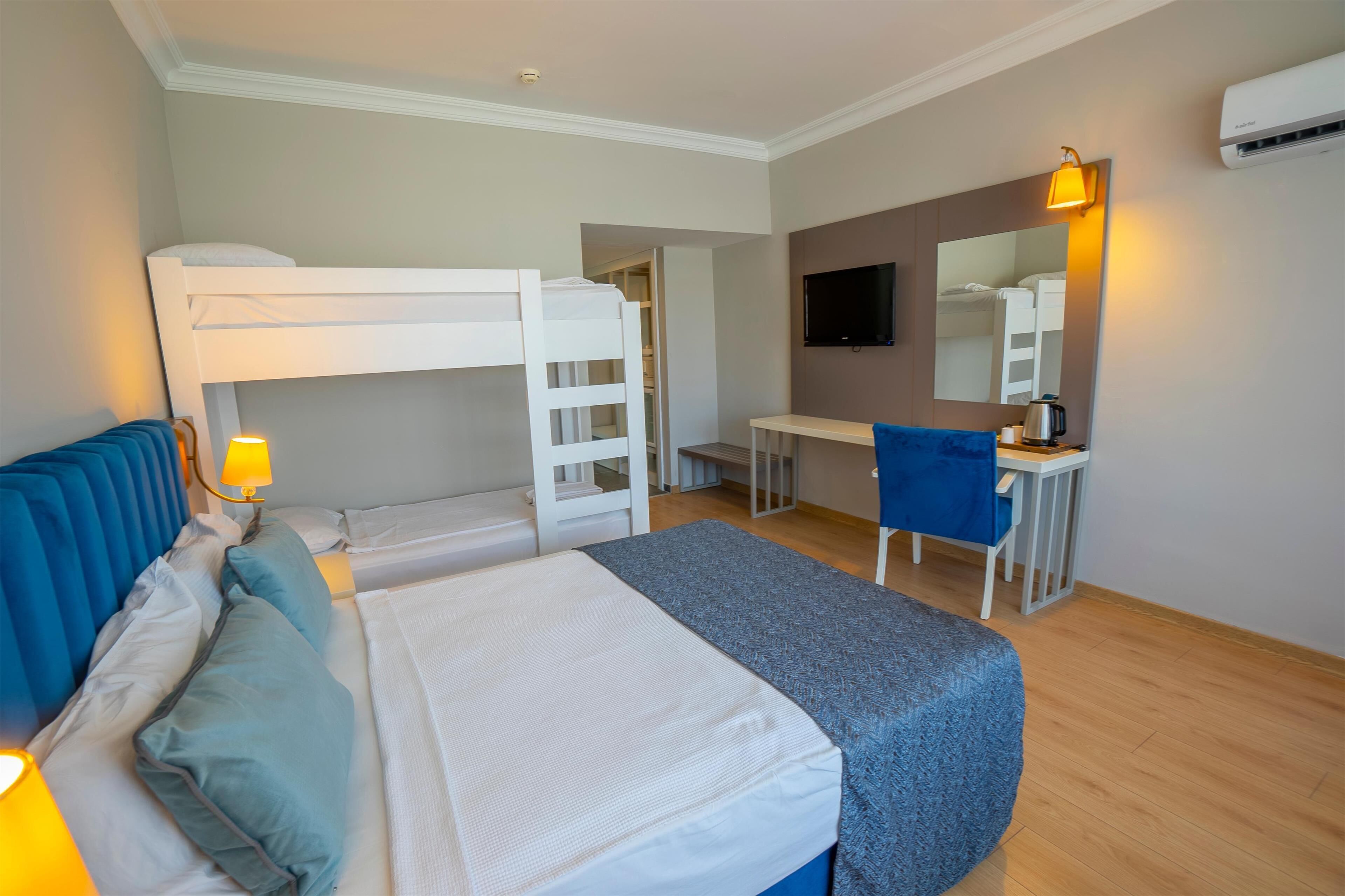 A bedroom with a bunk bed, a desk, a chair, a television, and an air conditioning unit.