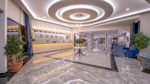 A modern hotel lobby with a marble floor, a reception desk, and a chandelier. - Armas Bella Sun - All Inclusive (Manavgat)