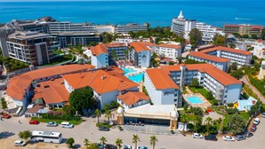 A hotel complex with multiple buildings, a swimming pool, and a view of the sea. - Armas Bella Sun - All Inclusive (Manavgat)