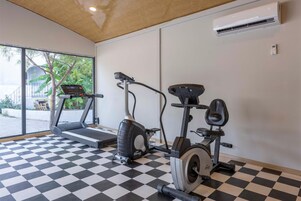 Un gimnasio con suelo a cuadros, máquinas de cardio y un equipo de aire acondicionado.